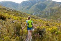 Ein Teenager-Mädchen läuft mit einem Rucksack auf einem Pfad in den Bergen — Stockfoto