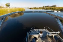 Un ragazzo su un motoscafo che viaggia lungo un corso d'acqua nel delta dell'Okavango — Foto stock