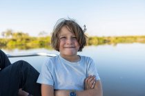 Un niño en una lancha que viaja por un canal en el delta del Okavango - foto de stock