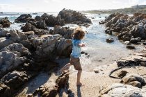 Восьмилетний мальчик исследует скалистый пляж — стоковое фото