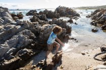 Восьмирічний хлопчик досліджує скелястий пляж — стокове фото