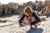 Девочка-подросток собирает ракушки на песчаном пляже — стоковое фото