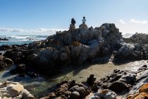 Duas crianças, uma adolescente e um menino de oito anos explorando as rochas irregulares e as piscinas de rochas em uma praia. — Fotografia de Stock
