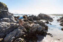 Niño de ocho años explorando una playa rocosa - foto de stock