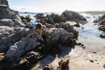 Garçon de huit ans explorant une plage rocheuse — Photo de stock