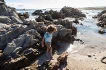 Otto anno vecchio ragazzo esplorando un roccioso spiaggia — Foto stock