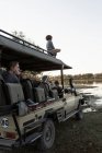 Garçon de huit ans au-dessus du véhicule safari avec passagers — Photo de stock