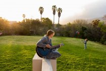 Teenage girl playing guitar and singing outdoors — Stock Photo