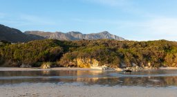 Paisagem de bosques e montanhas, uma pequena praia de areia protegida na costa atlântica. — Fotografia de Stock