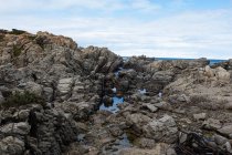 Costa irregular rochosa, piscina de rocha e vista para o oceano — Fotografia de Stock