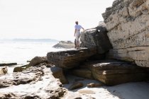 Teenage girl exploring the cliffs and rock strata on a beach on the Atlantic shore. — Stockfoto