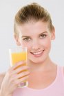 Woman looking at camera holding glass of orange juice. — Stock Photo