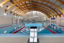 Indoor swimming pool, starting block, diving block and marked lanes, flat calm water — Foto stock