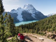 Two people resting by a hiking path, view of Mount Robson and the Rockies. — Stock Photo