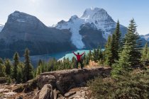 Man with arms raised, on a ridge above Berg lake and mountains. — Stockfoto
