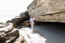 Ragazza adolescente che esplora le scogliere e gli strati rocciosi su una spiaggia sulla riva atlantica. — Foto stock