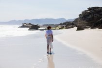 Дівчинка-підліток, що йде на піщаному пляжі на краю води — стокове фото