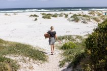 Adult woman carrying picnic basket on Grotto Beach, Hermanus, Western Cape, South Africa. — Stockfoto