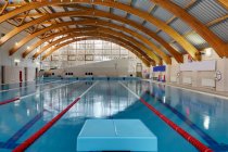 Indoor swimming pool with marked lanes, flat calm water and diving block — Stockfoto