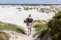 Adult woman carrying picnic basket on Grotto Beach, Hermanus, Western Cape, South Africa. — Stockfoto