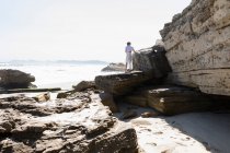Adolescente explorando as falésias e estratos de rocha em uma praia na costa atlântica. — Fotografia de Stock