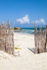 An opening in the fence onto a white sand beach — Stock Photo