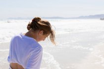 Teenage girl walking on a sandy beach at the water's edge — Stock Photo