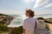 Teenage girl standing on top of a cliff looking over the coastline and inlet. — Stock Photo