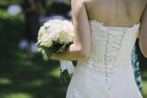 A bride in a fitted bodice, white dress with lacings across the fitted back panels. — Stock Photo