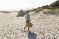 Ragazza adolescente che cammina lungo la sabbia portando un cesto. — Foto stock