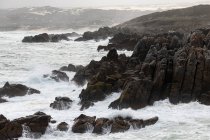 Jagged rocks and the rocky coastline of the Atlantic at De Kelders beach, waves breaking on shore. — Stock Photo
