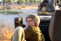 A boy sitting in a jeep on a safari drive at sunrise — Stock Photo