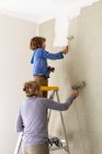 Uma mulher e um menino de oito anos decorando um quarto, pintando paredes. — Fotografia de Stock