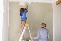 Жінка і восьмирічний хлопчик прикрашають кімнату, малюють стіни . — стокове фото