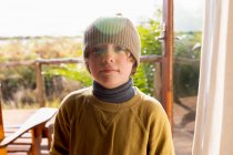 Portrait of young boy in a woolly hat on a terrace — Stock Photo