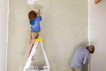 Eine Frau und ein achtjähriger Junge dekorieren ein Zimmer, streichen Wände. — Stockfoto
