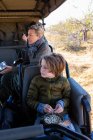 Giovane ragazzo seduto in un veicolo safari mangiare noccioline. — Foto stock