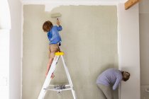 Una mujer y un niño de ocho años decorando una habitación, pintando paredes. - foto de stock