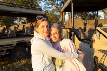 Una madre abrazando a su hija adolescente en unas vacaciones de safari familiar. - foto de stock