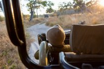 Un jeune garçon assis dans une jeep sur un safari au lever du soleil. — Photo de stock