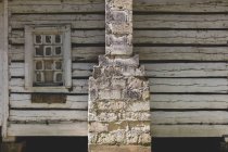 Uma cabine de madeira abandonada com chaminé de pedra, rachada e seca o revestimento de madeira e a janela quebrada. — Fotografia de Stock