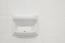 Un mur de carrelage blanc d'une salle de bain ou d'une salle de douche, avec un évidement en porcelaine en forme. Un bloc de savon. — Photo de stock
