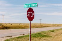 Prairie Home sign and stop sign at the side of a road. — Foto stock