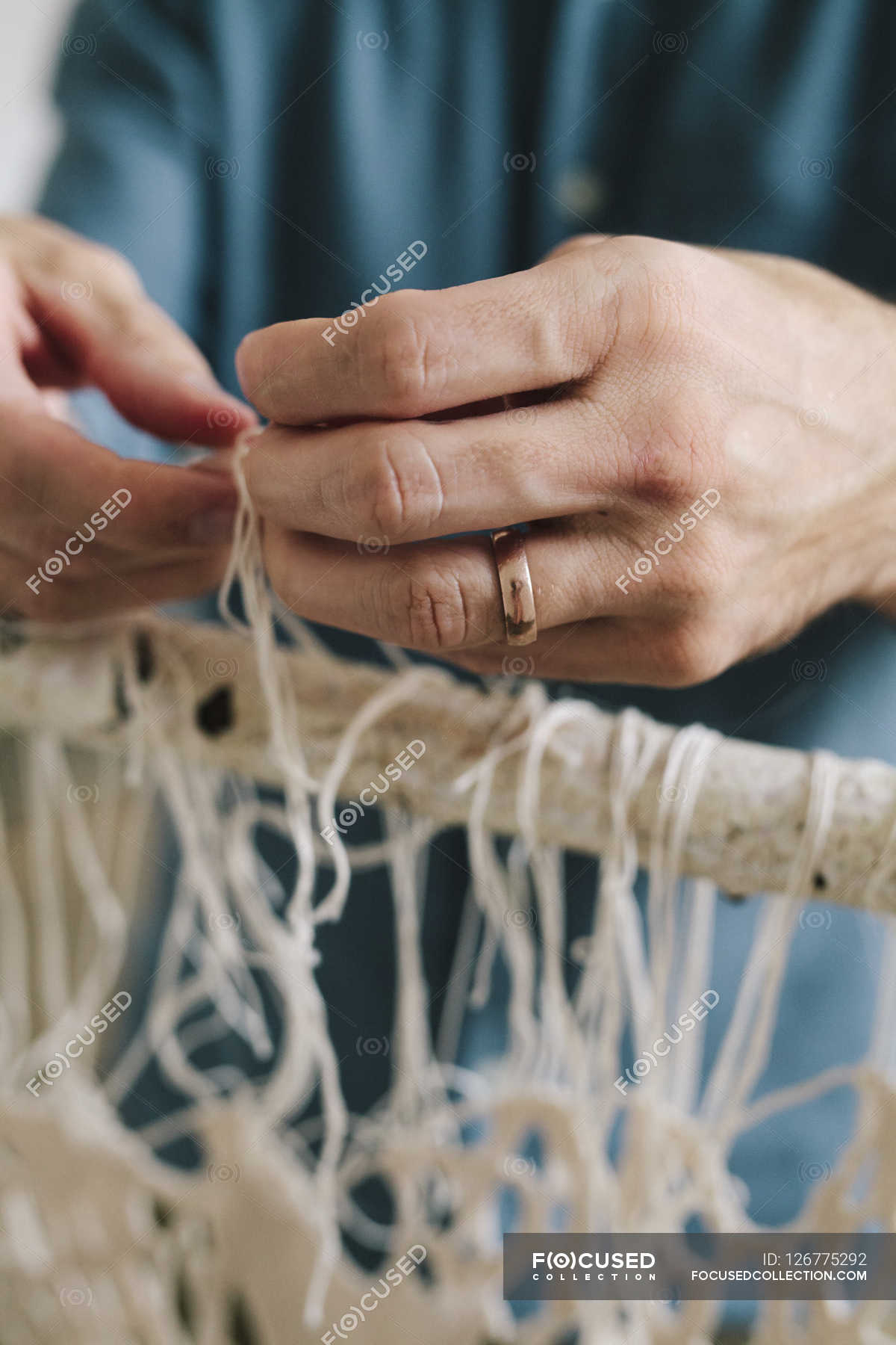 Male artist knotting and weaving threads. — daylight, hands Stock Photo 126775292