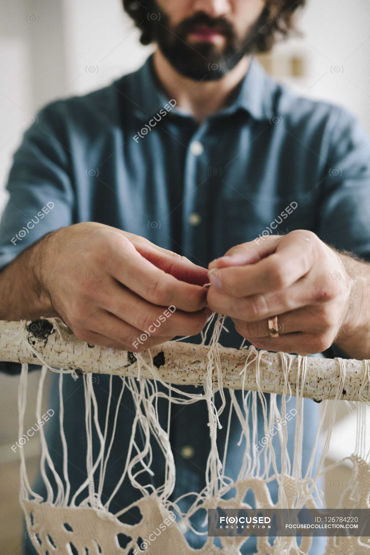 Male artist knotting and weaving threads. — intricate, minimal Stock Photo 126784220