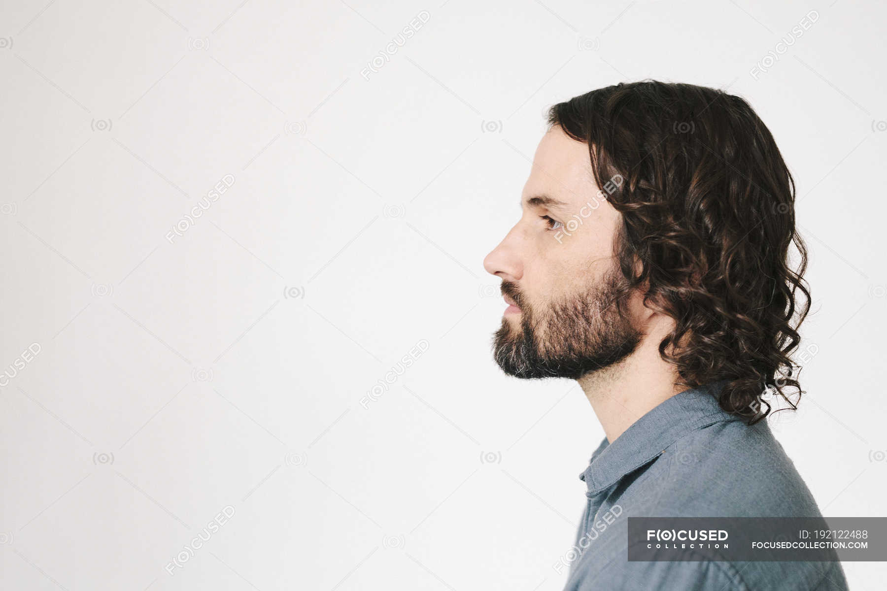 Head and shoulders of young man with beard, side view. — shirt, looking