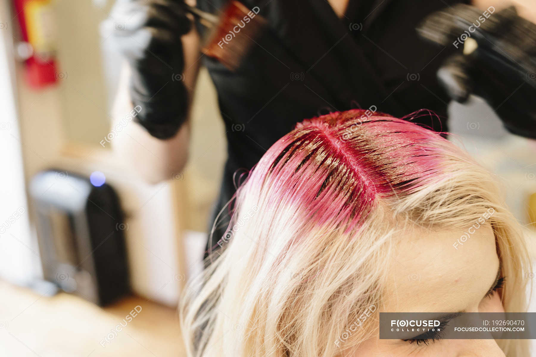 Female Hair Colorist In Gloves Applying Red Hair Dye To Client