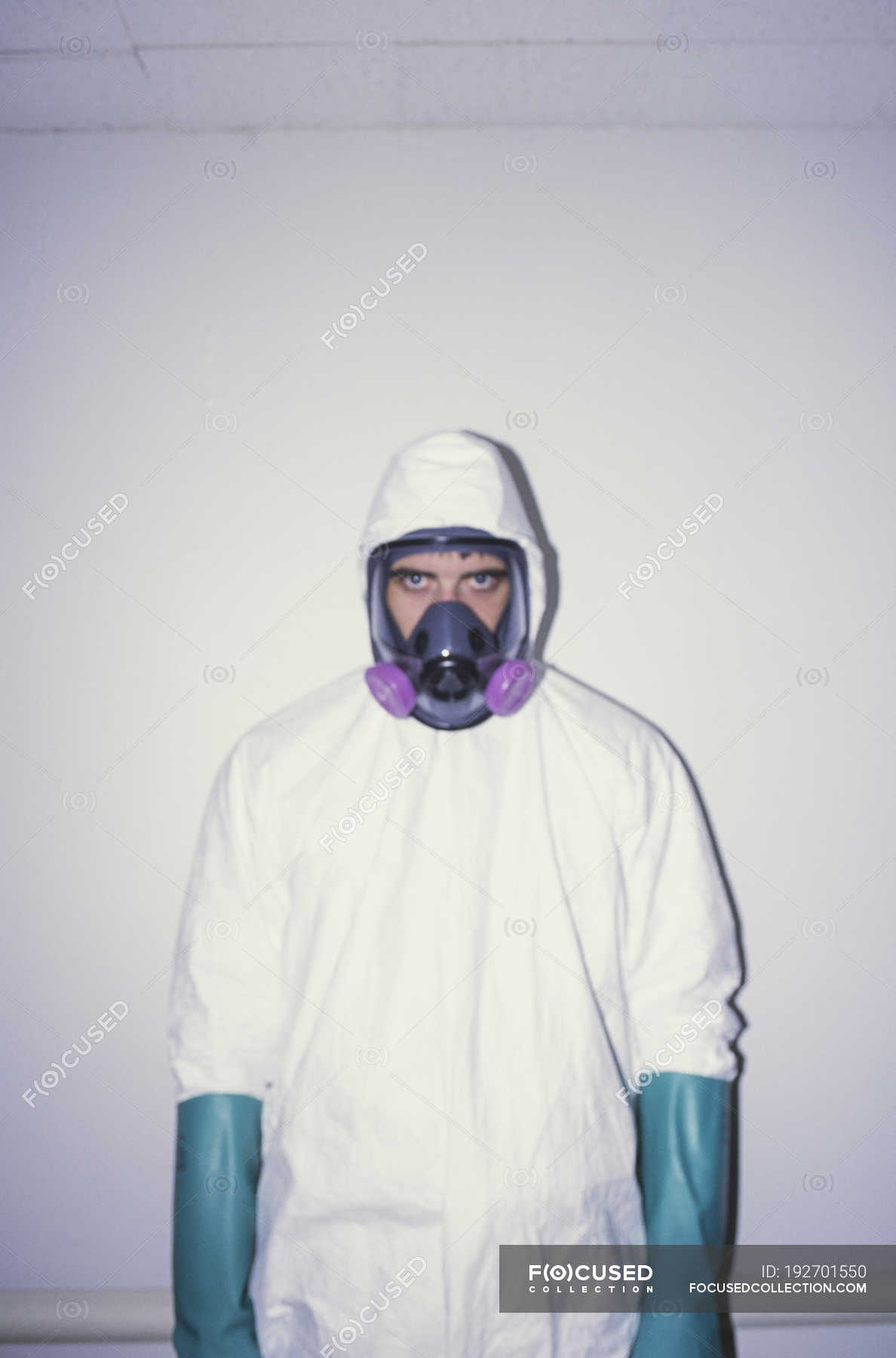 Man in white protective clean suit, blue gloves and breathing mask