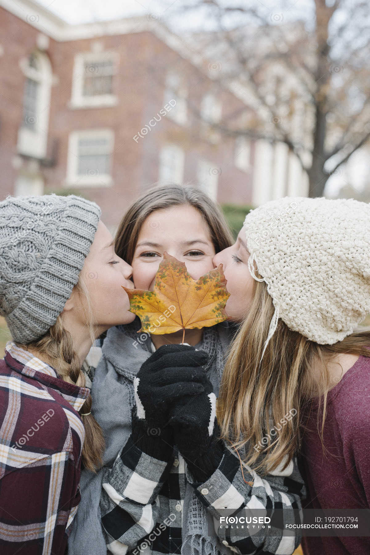 Teenage Girls Kissing On Cheek S Friend With Autumn Leaf In Front Of Face Autumnal Outdoors Stock Photo
