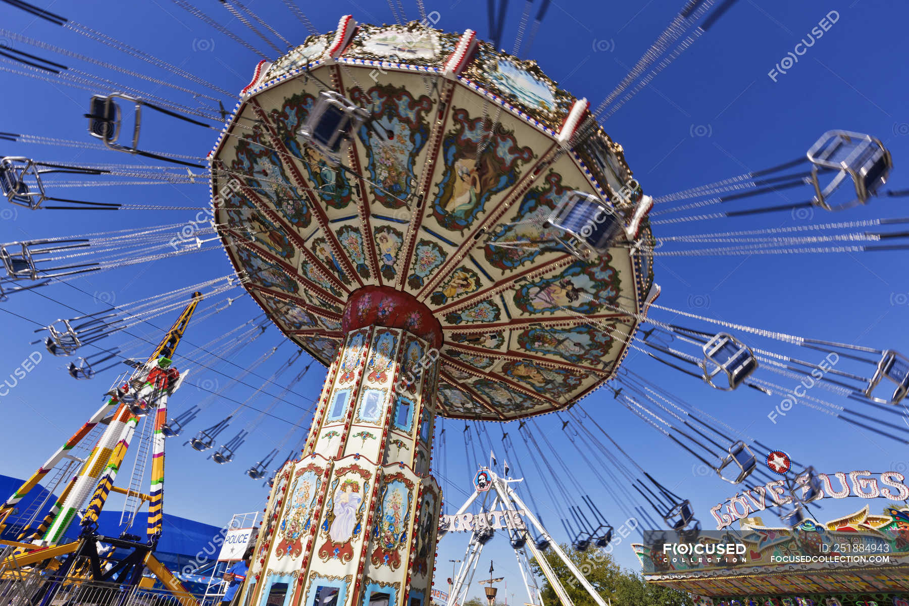 Low Angle View Of Chain Swing Ride Against Blue Sky At Fair Park In